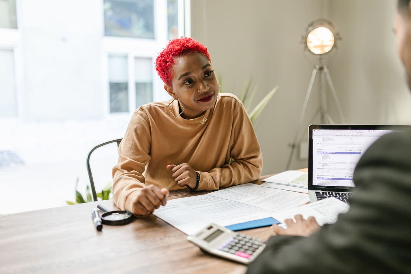 A consultant going through paperwork with a client across a desk
