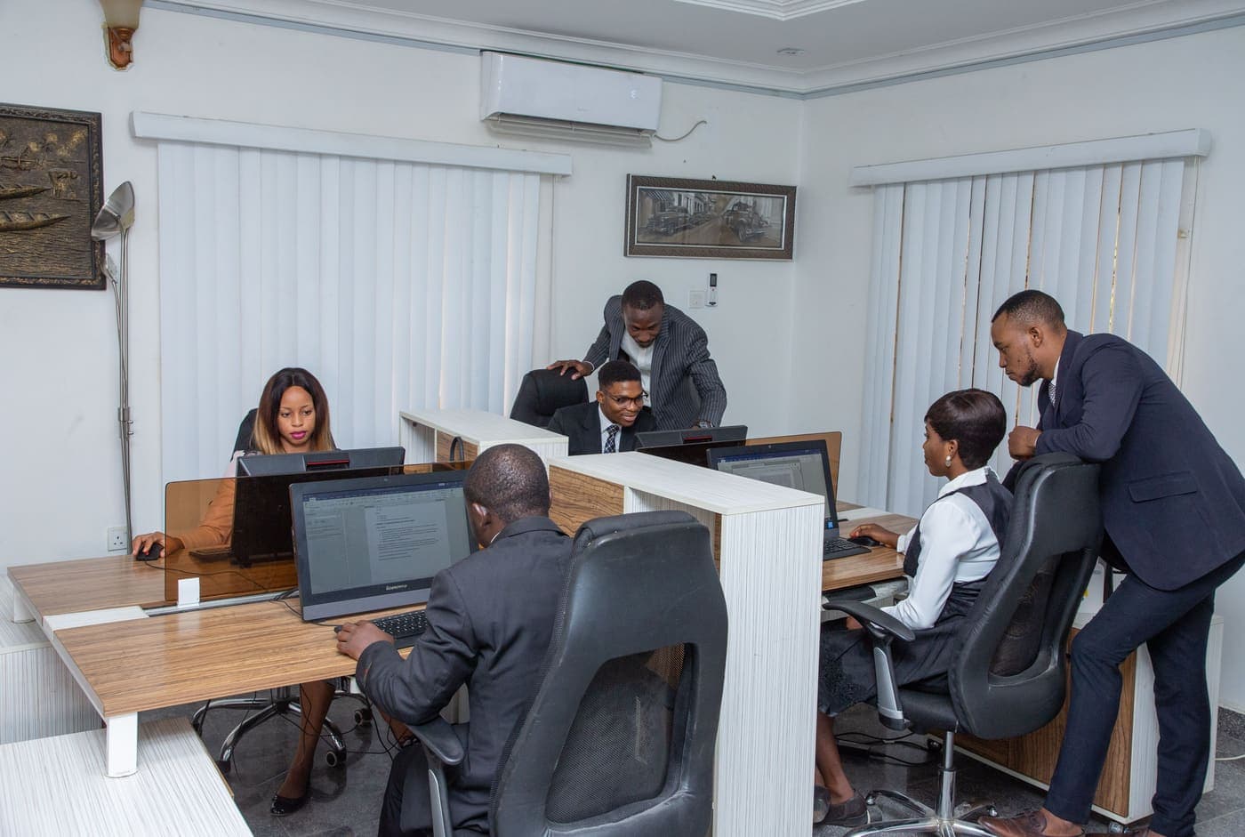 Five colleagues working at desks in an open-plan travel office