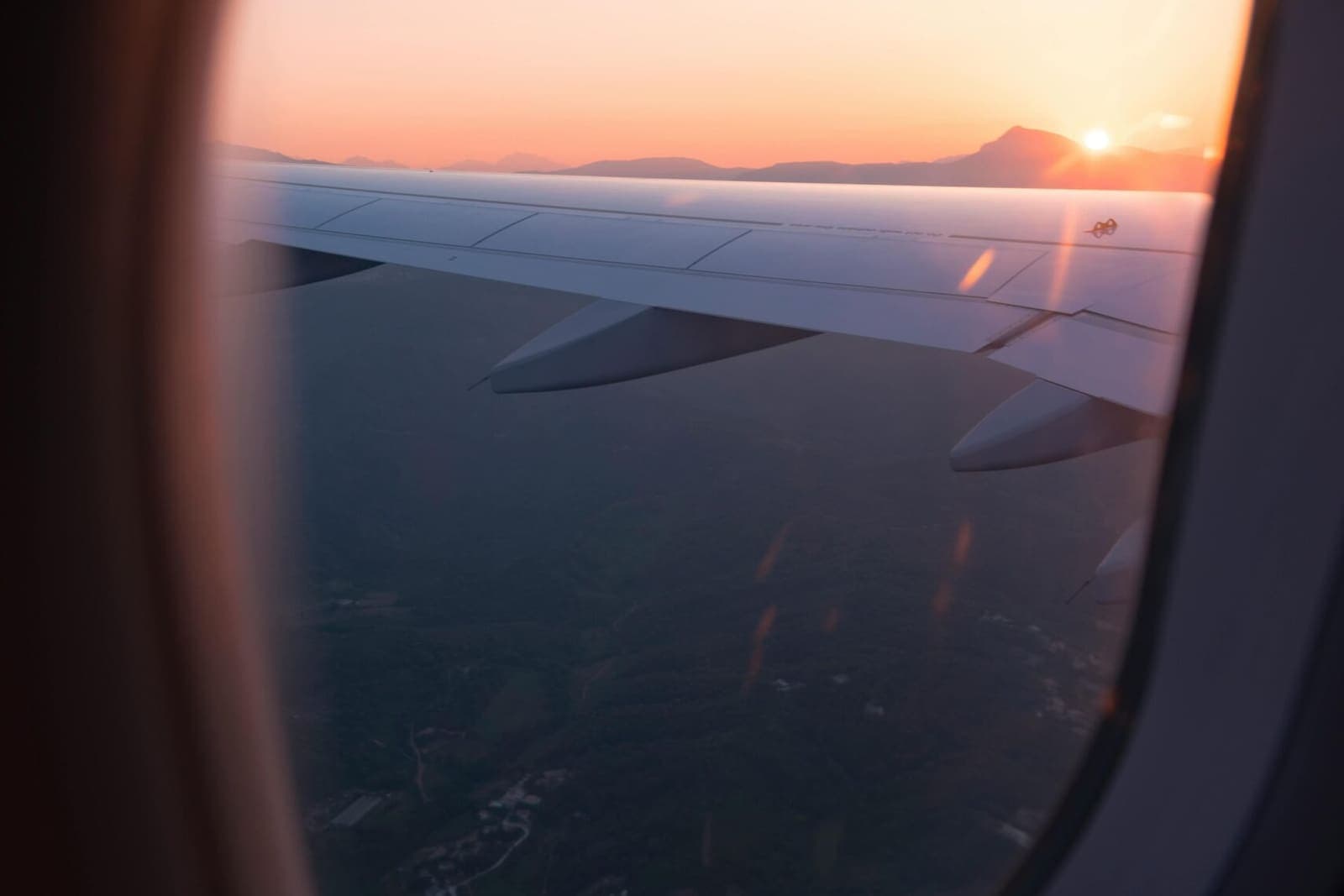 A wing and the sunrise seen through a cabin window