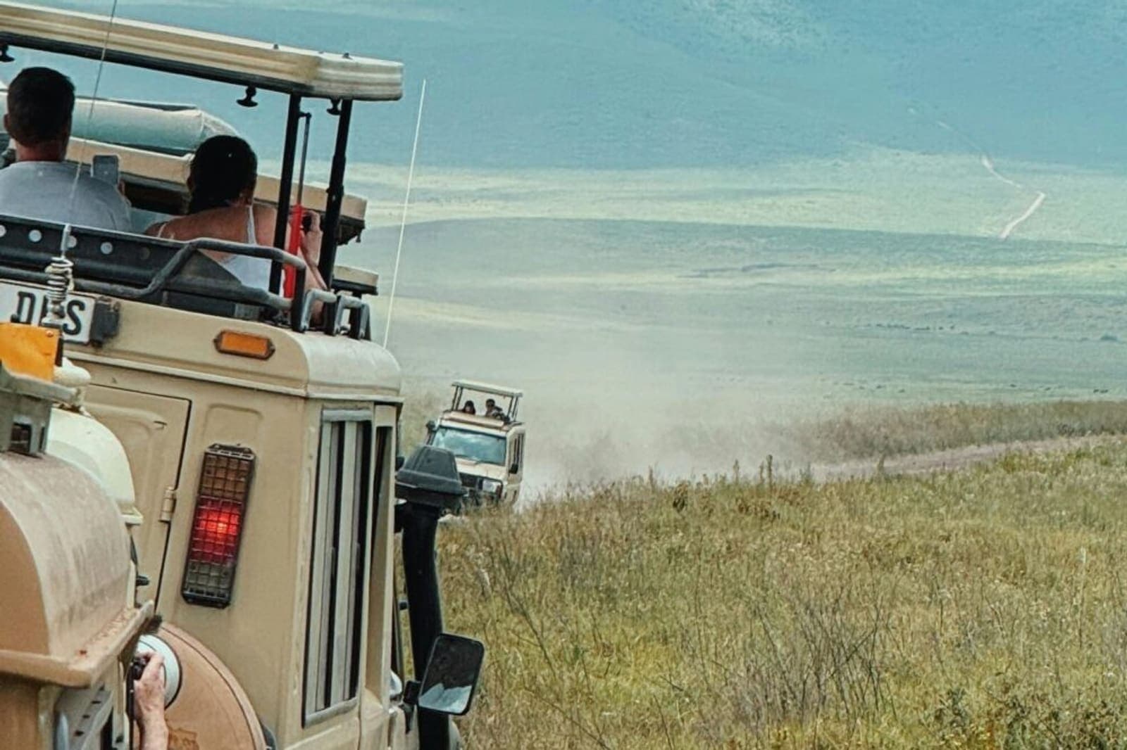 Guests being driven across open country in a safari vehicle